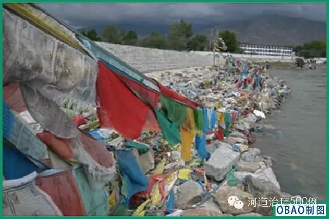 掛在石籠護岸上的經幡，失去了表達的自然載體